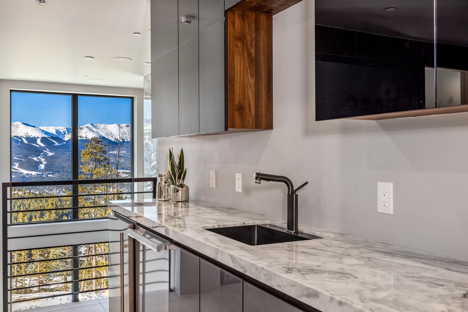 Savor your morning coffee in this sleek kitchen while taking in breathtaking mountain views through floor-to-ceiling windows.