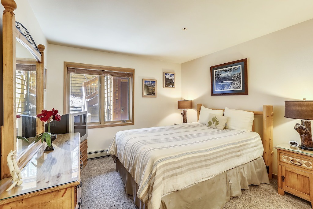 Sink into soft linens in your cozy bedroom, where natural light streams through windows and mountain artwork creates a peaceful retreat.