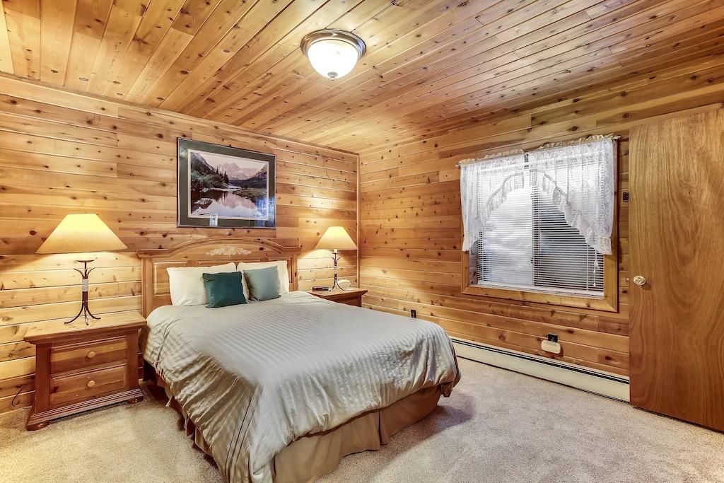 Cozy cabin bedroom with warm wood walls and soft lighting where you'll drift off to peaceful mountain dreams.