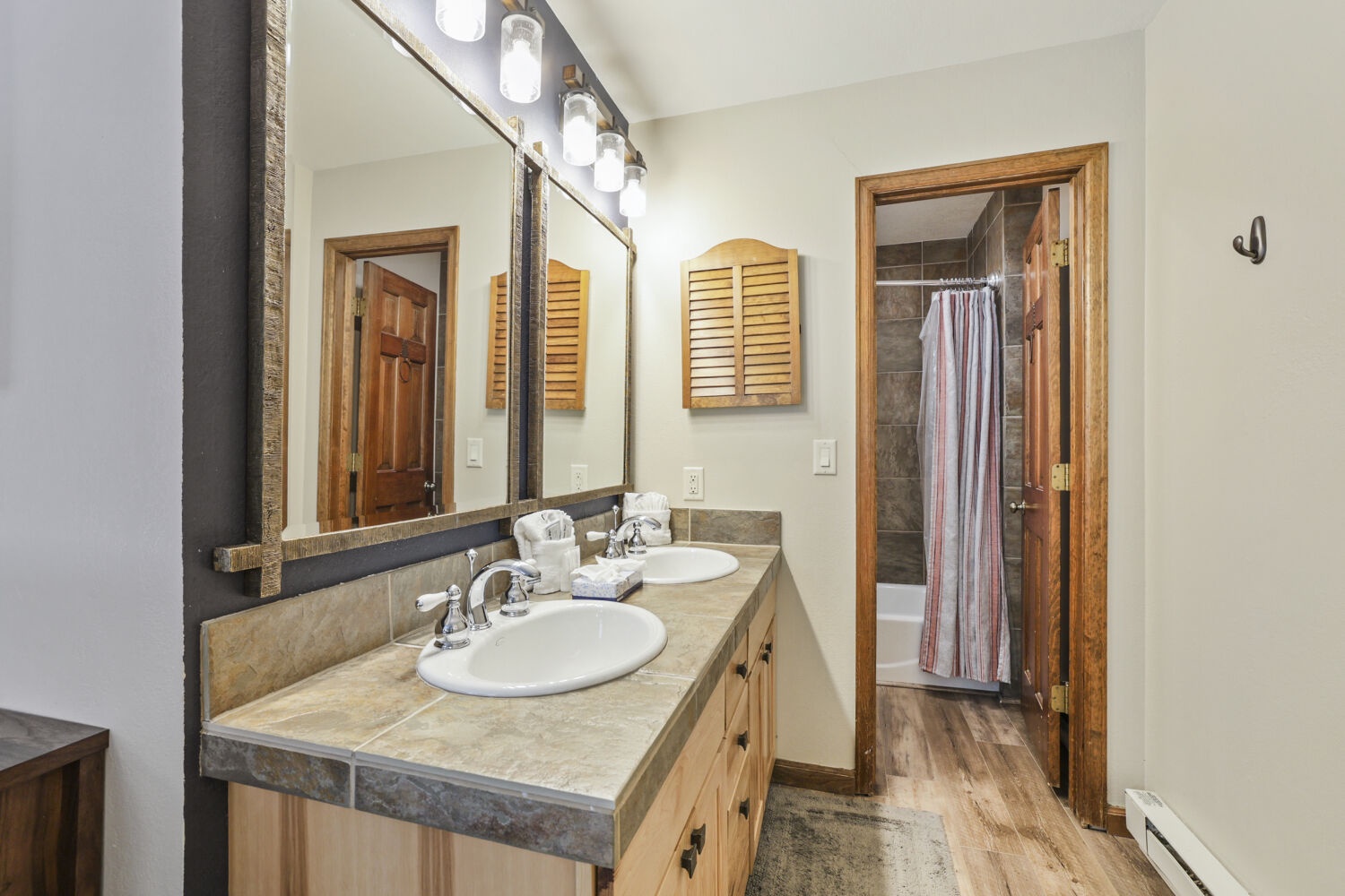 Freshen up in this spacious bathroom featuring dual sinks, rustic wood accents, and easy access to your private shower—everything you need for a comfortable stay.