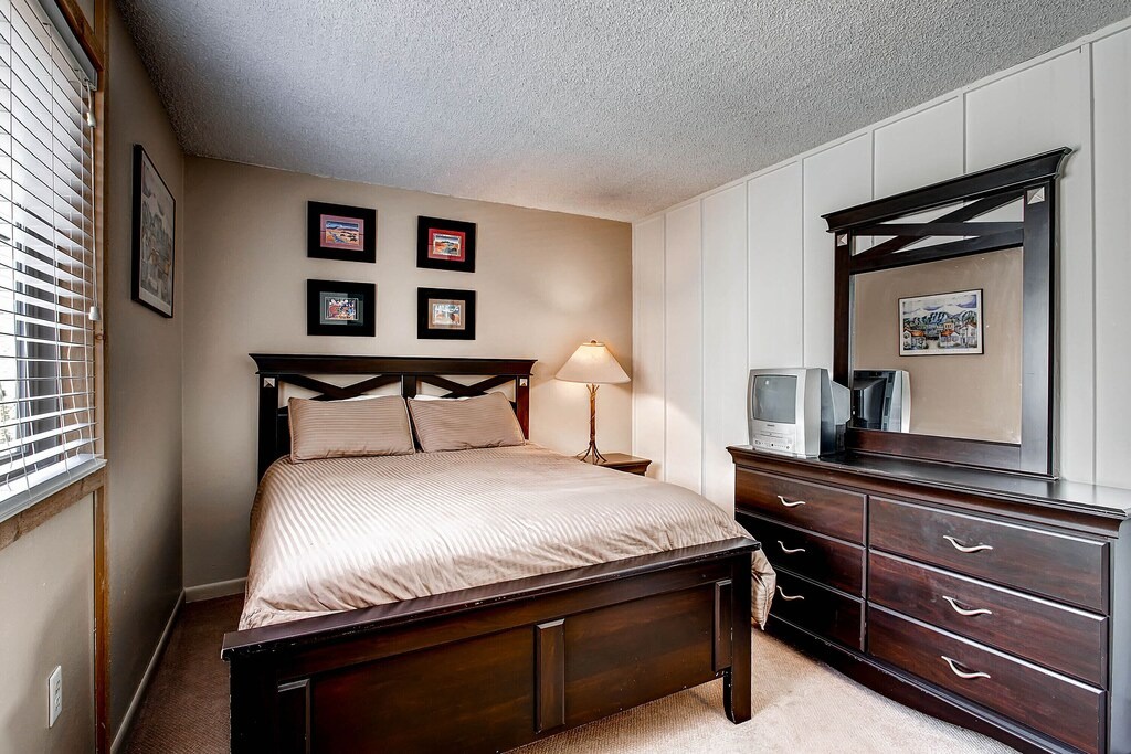 Unwind in your comfortable bedroom featuring rich wood furnishings, crisp linens, and thoughtful amenities for a restful stay.
