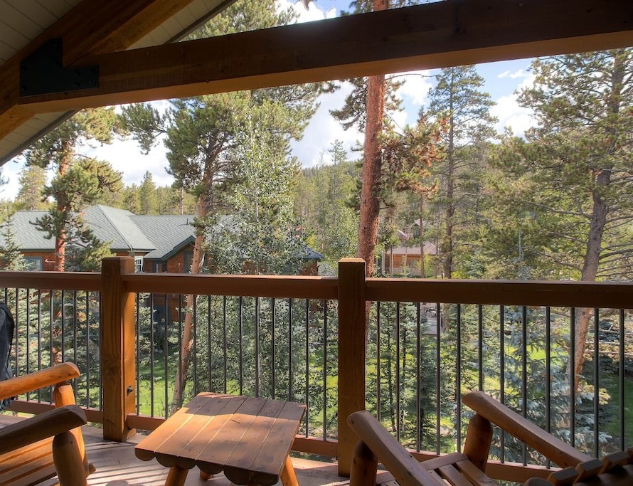 Relax on your private balcony with forest views, where rustic wooden furniture invites you to unwind among the peaceful treetops.