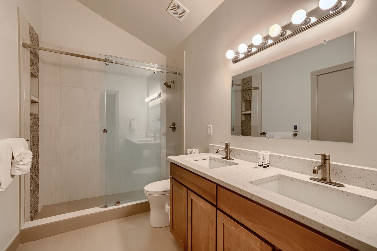 Unwind in your spacious bathroom featuring dual sinks, elegant quartz countertops, and a luxurious walk-in shower with beautiful tile accents.