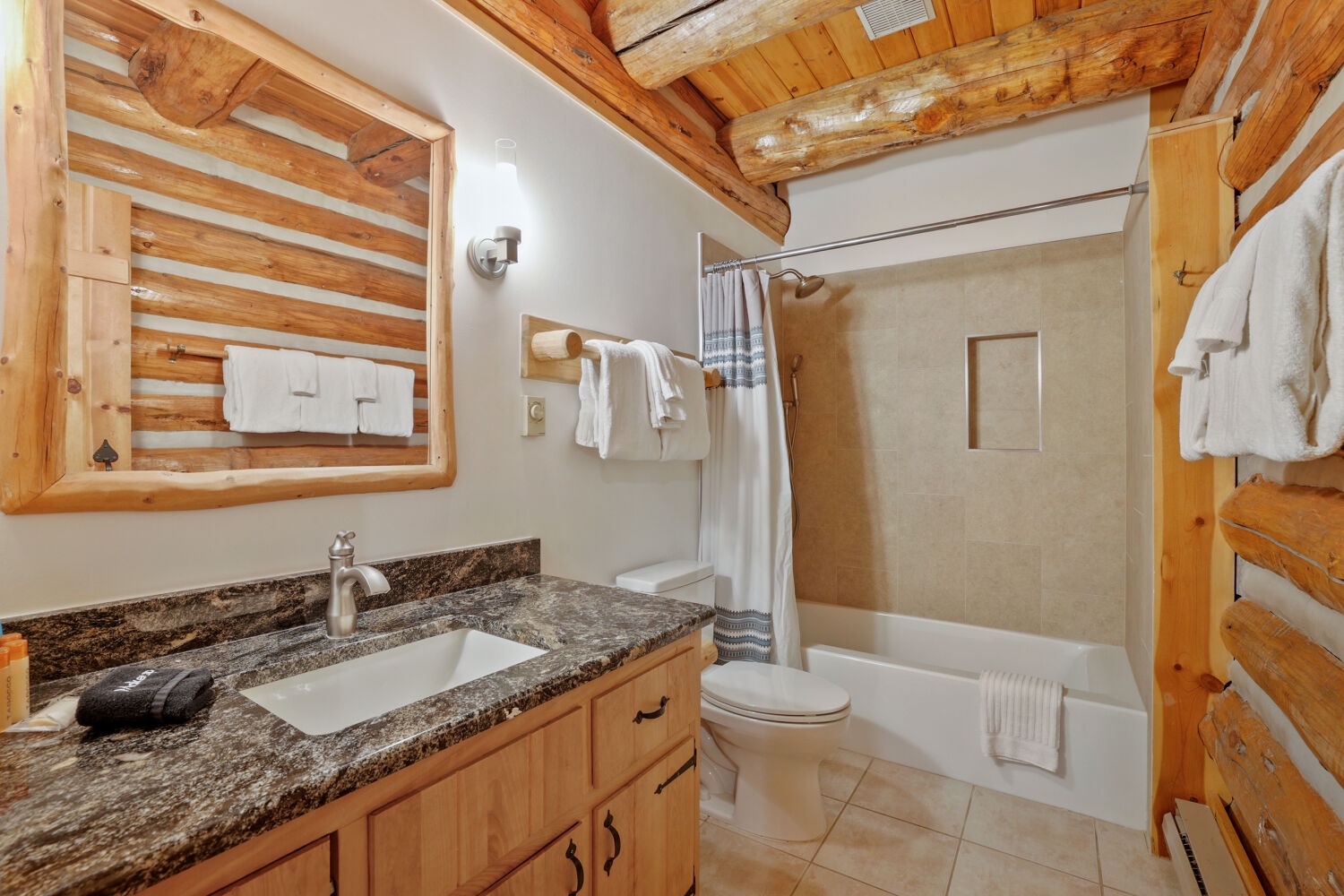 Rustic charm meets modern comfort in your private bath, where warm log beams and granite counters create a cozy yet polished retreat after a day of mountain adventures.