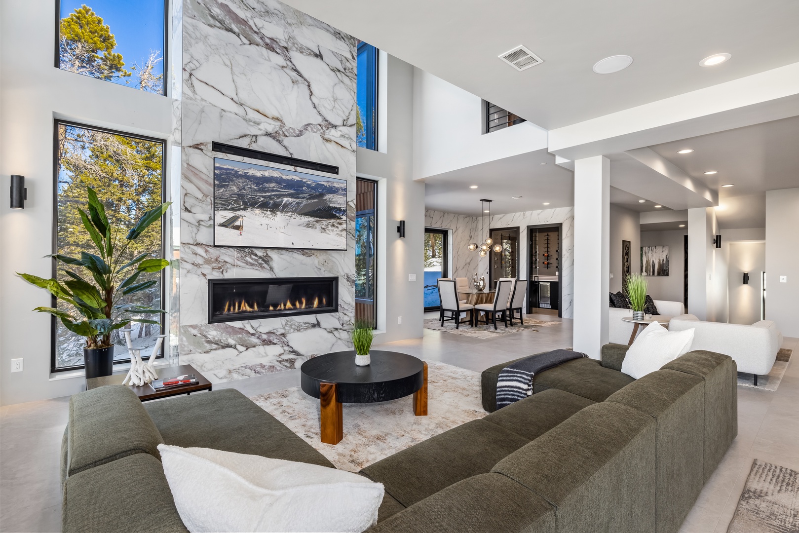 Relax in this stunning open-concept living space featuring marble fireplace, soaring ceilings, and seamless flow to your dining area.