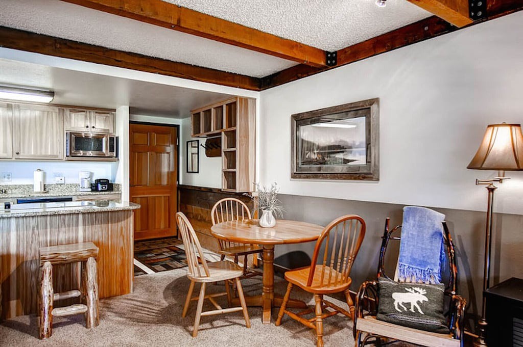 Cozy up by the fireplace in this charming space featuring rustic wood beams, a fully equipped kitchen, and warm dining area.