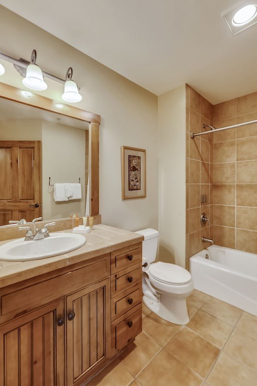 Your private bathroom features warm wood vanity, tiled shower-tub combo, and bright lighting for comfortable daily routines.