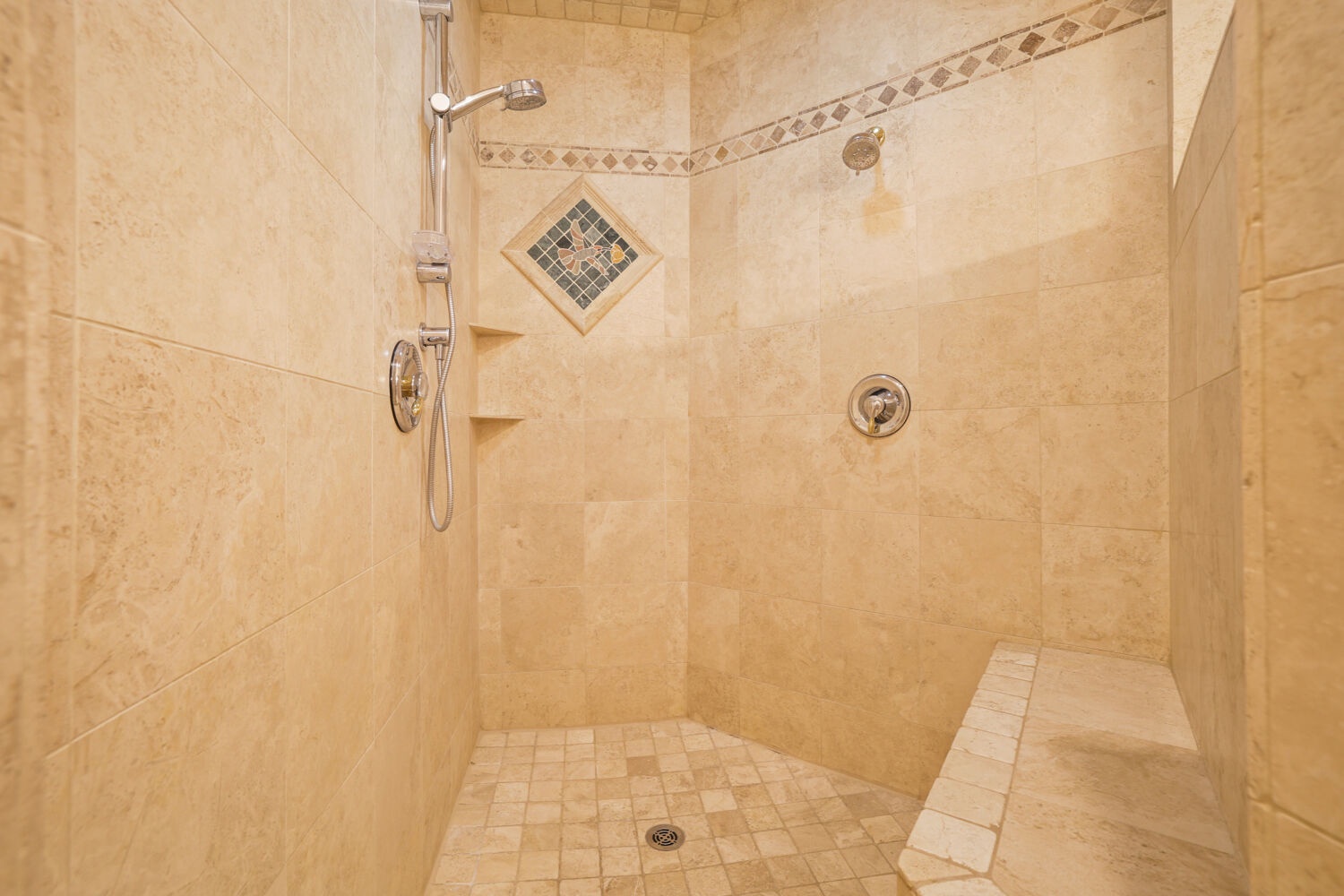 Step into your spacious walk-in shower with custom tilework, dual showerheads, and a built-in bench—a perfect way to refresh after a day of exploring.