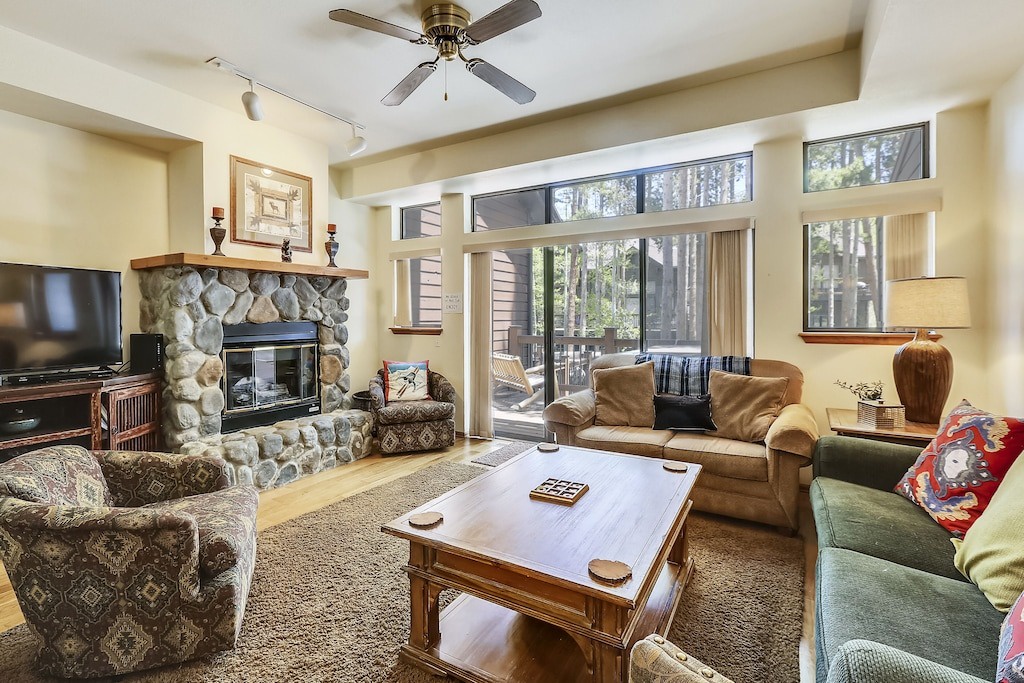 Unwind in your spacious living room with a crackling stone fireplace and peaceful forest views through expansive windows.