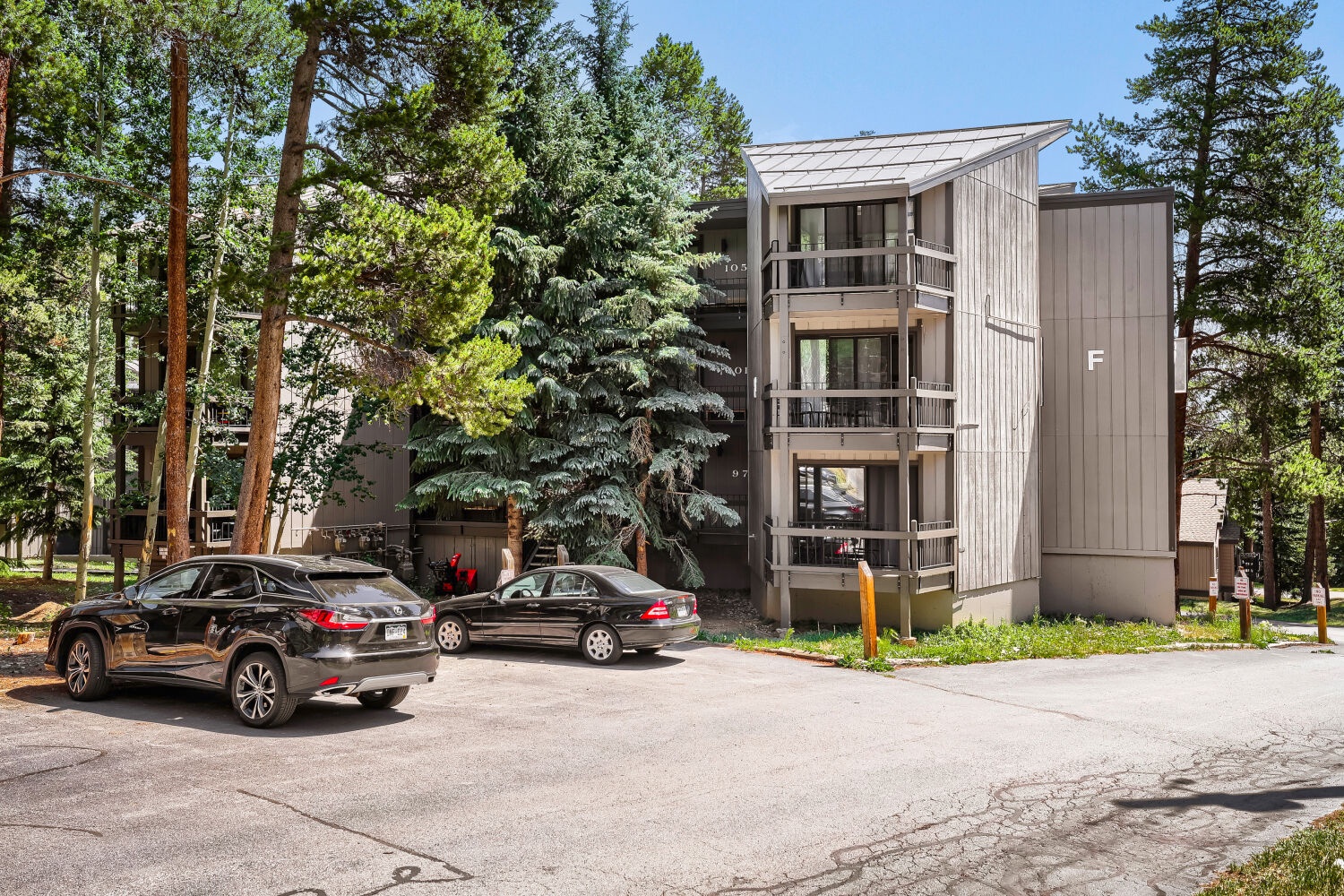 Modern multi-story property nestled among towering pines with convenient parking and balconies, located in a tranquil mountain setting.