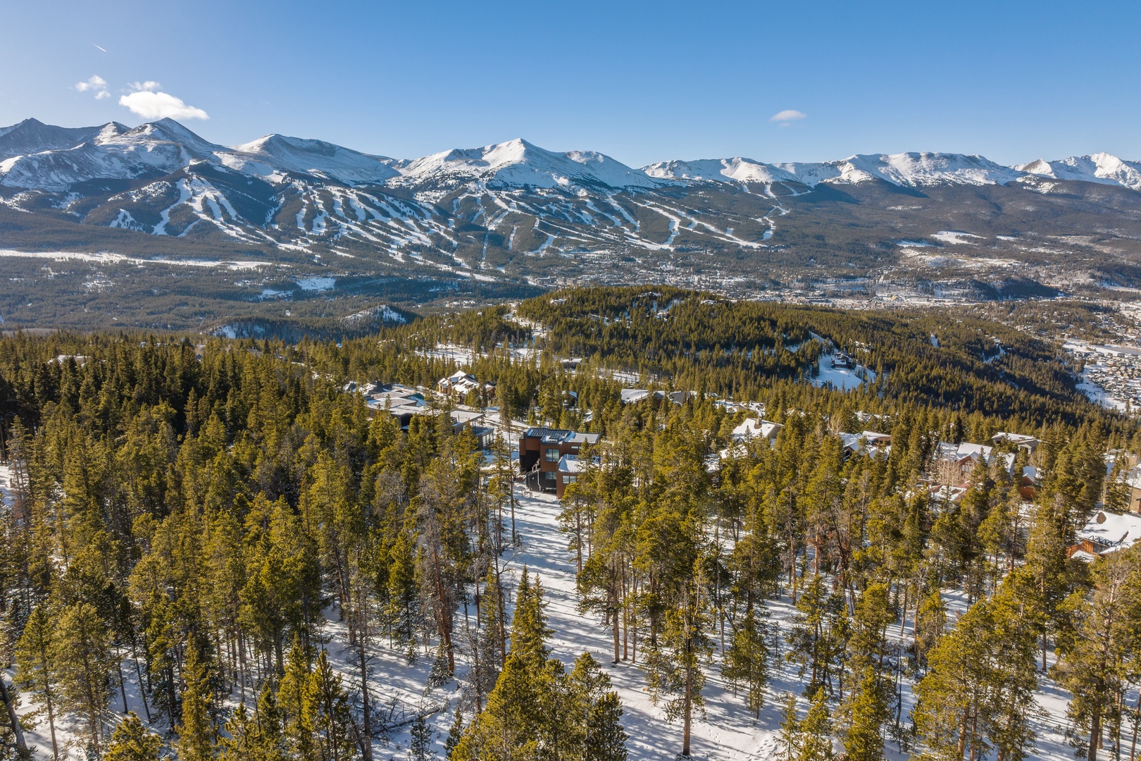 Stunning aerial view showcases snow-capped peaks and pristine wilderness surrounding this mountain retreat destination.