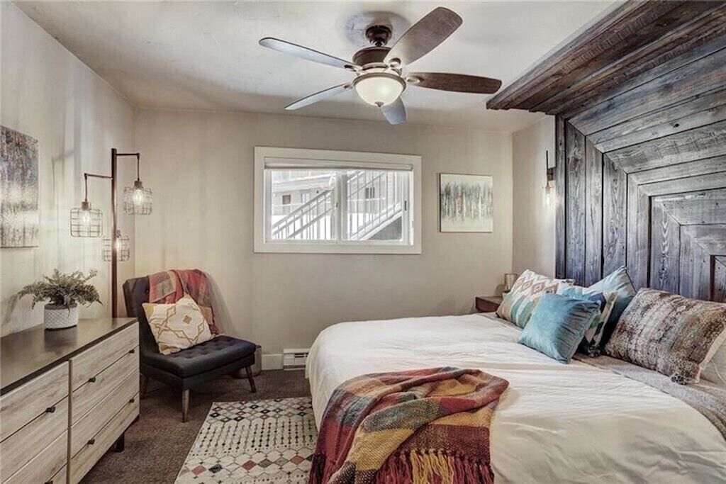 Drift off to peaceful sleep in your cozy bedroom, complete with rustic wood headboard and cooling ceiling fan for perfect comfort.