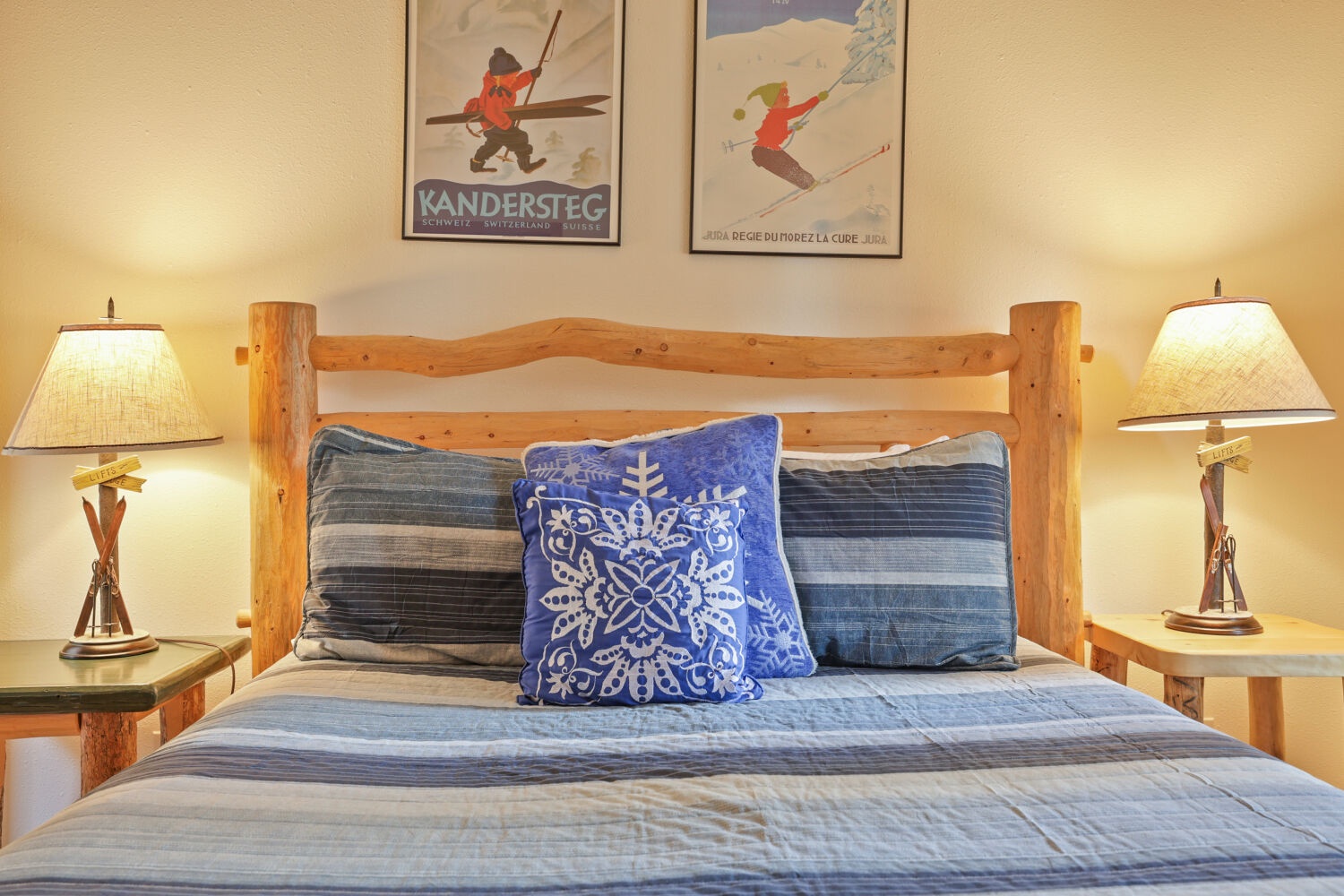 Rest easy in this cozy bedroom with rustic log-frame furniture and warm alpine touches. Vintage ski posters hint at mountain adventures awaiting you nearby.