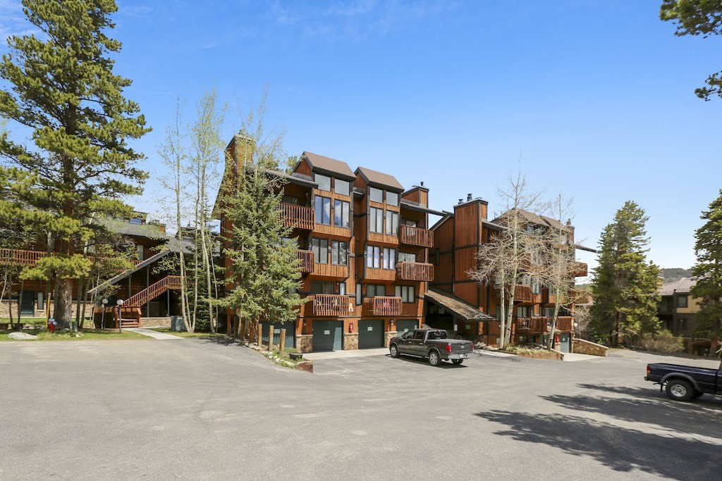 Multi-story mountain lodge with timber exterior and private balconies, nestled among tall pines with convenient parking.