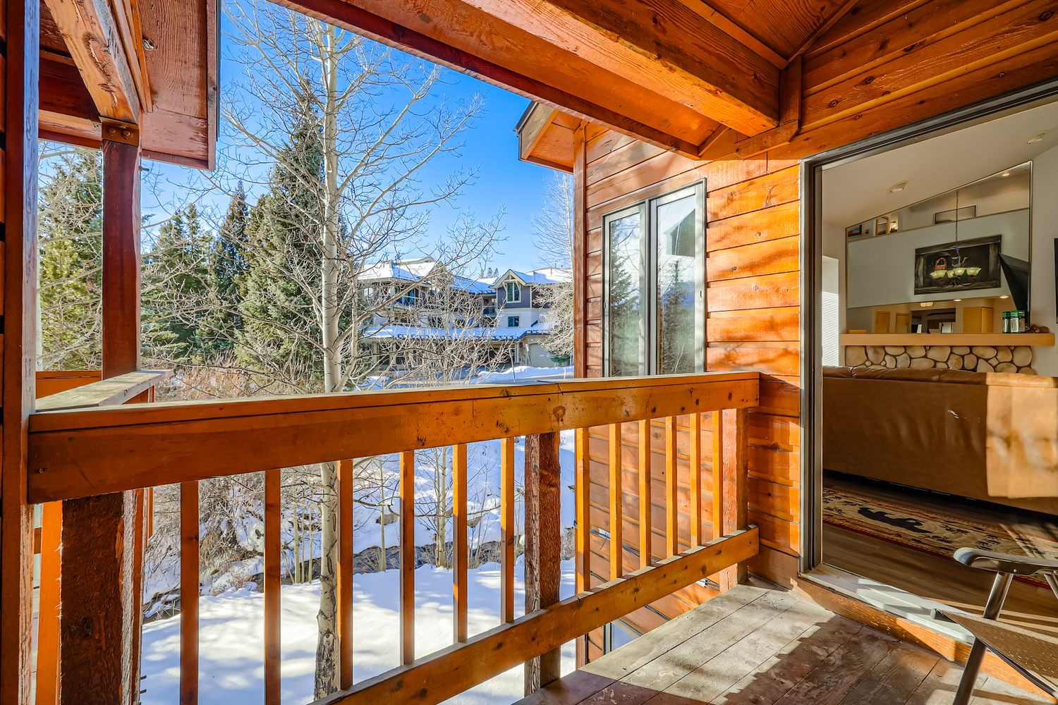 Step onto your private balcony where warm wood embraces snowy mountain views, creating the perfect winter retreat.
