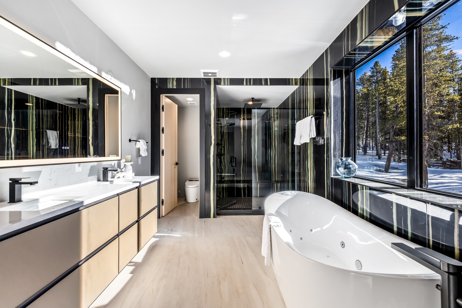 Luxurious spa-like bathroom with soaking tub, rainfall shower, and winter forest views for your ultimate relaxation.