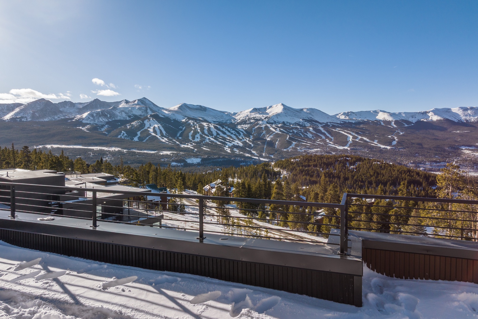 Stunning mountain panorama with snow-covered peaks and ski slopes stretching across the horizon from this elevated terrace.