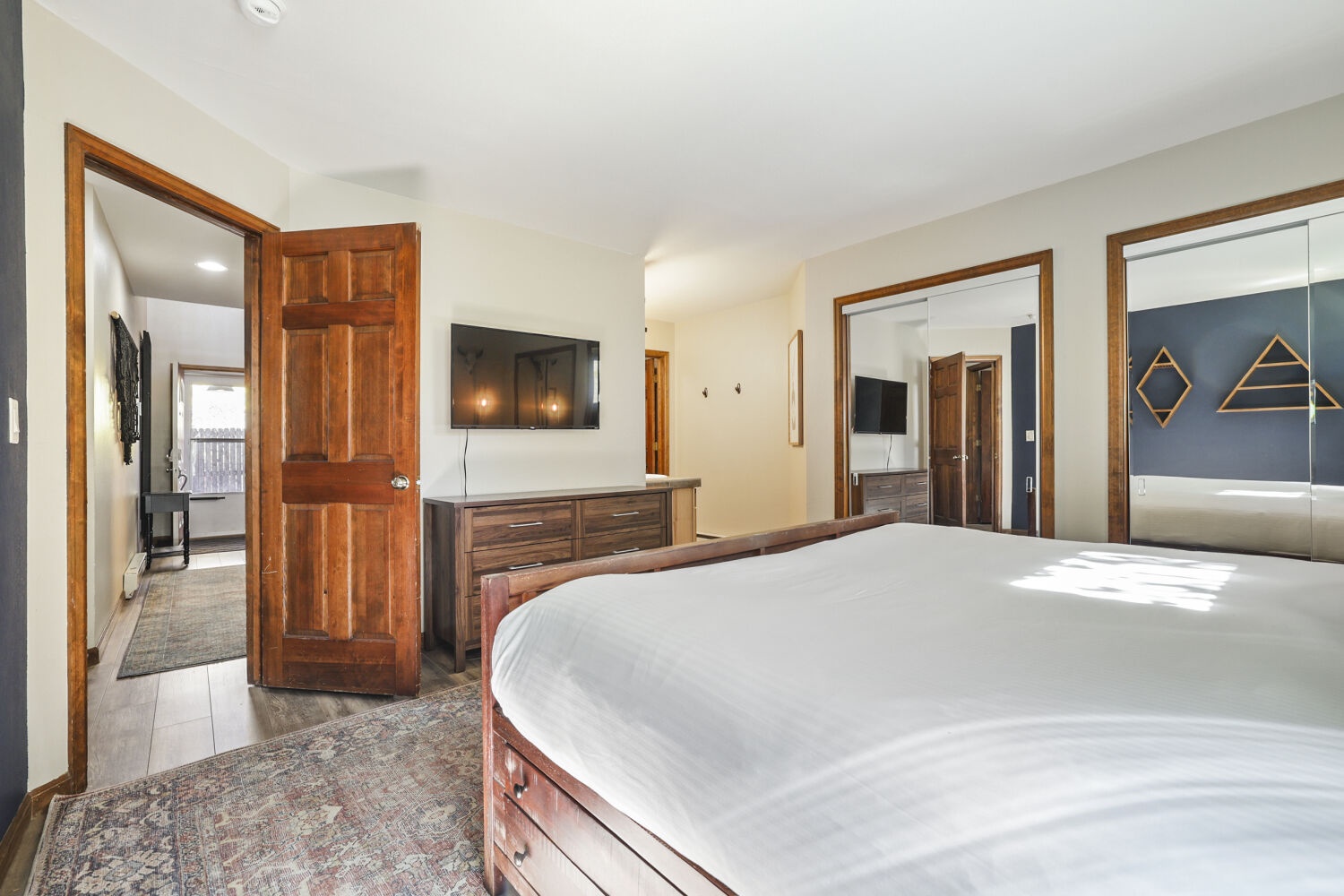 Step into your bright and airy bedroom, where warm wood tones meet crisp linens for a restful retreat. Sunlight streams in to highlight the polished furnishings and inviting bed that awaits your arrival.