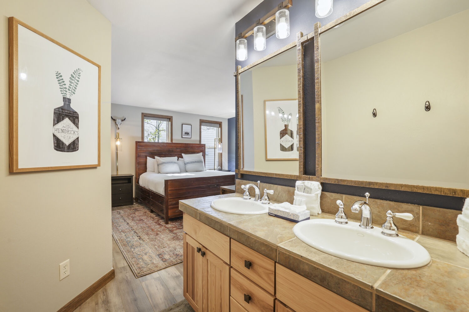 Step into your ensuite bathroom where farmhouse style meets modern comfort—dual sinks, warm wood accents, and fresh towels await after a day of mountain adventures.