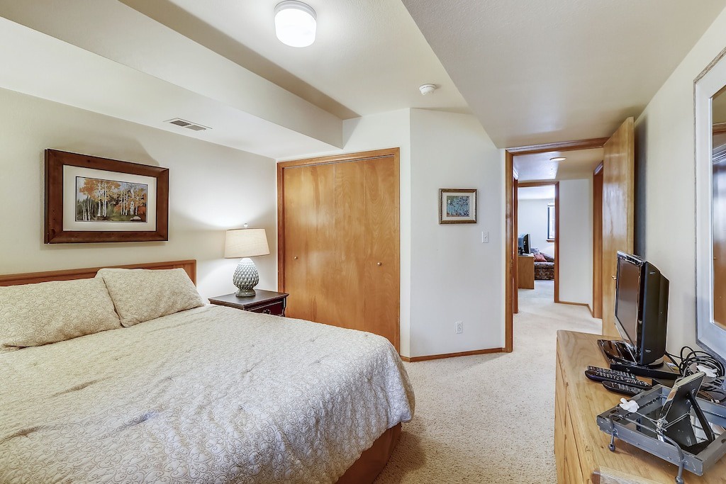 Relax in your cozy bedroom featuring warm wood tones, comfortable bedding, and modern amenities like a flat-screen TV for perfect downtime.