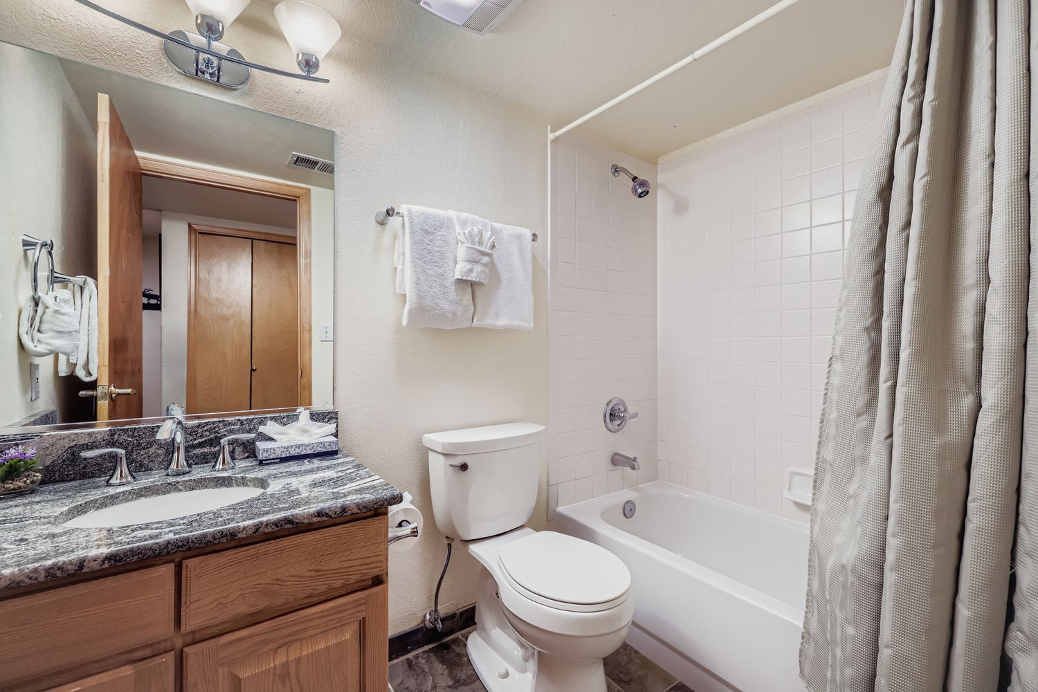 Your private bathroom features a relaxing tub-shower combo, granite vanity, and fresh towels waiting for your arrival.