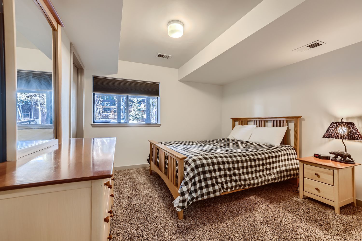 Your cozy bedroom features a comfortable bed with warm wood furnishings and peaceful forest views to help you unwind.