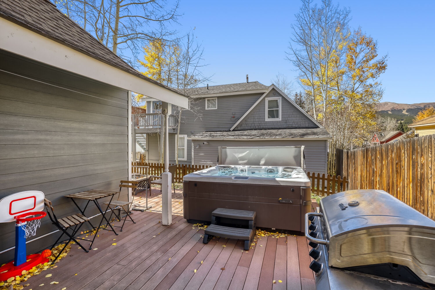 Your private backyard oasis awaits with a bubbling hot tub, spacious deck for grilling and dining, and mountain scenery framed by golden aspens—perfect for crisp autumn mornings or starlit evenings.