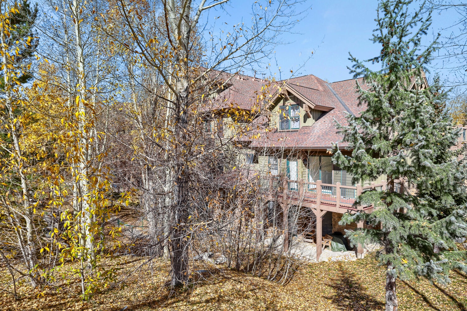 A welcoming mountain retreat nestled among evergreen pines and golden aspens, offering a private setting in a natural landscape.