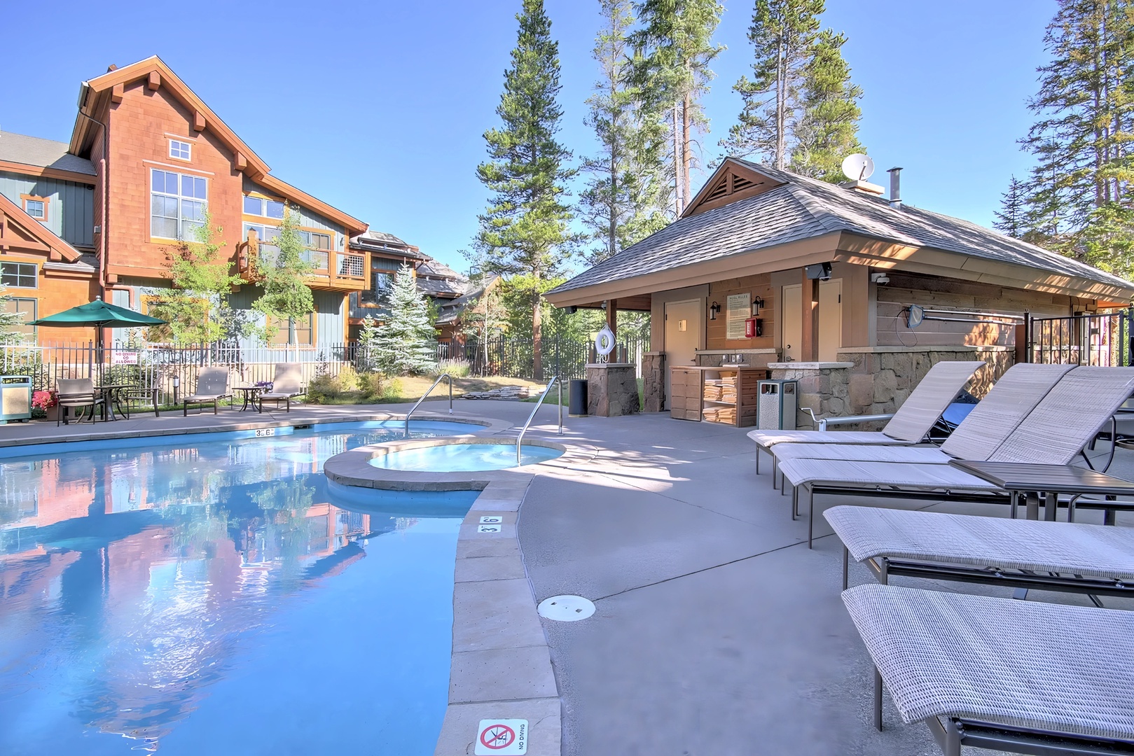 Spacious poolside retreat with comfortable loungers and mountain forest backdrop creates the perfect outdoor sanctuary.