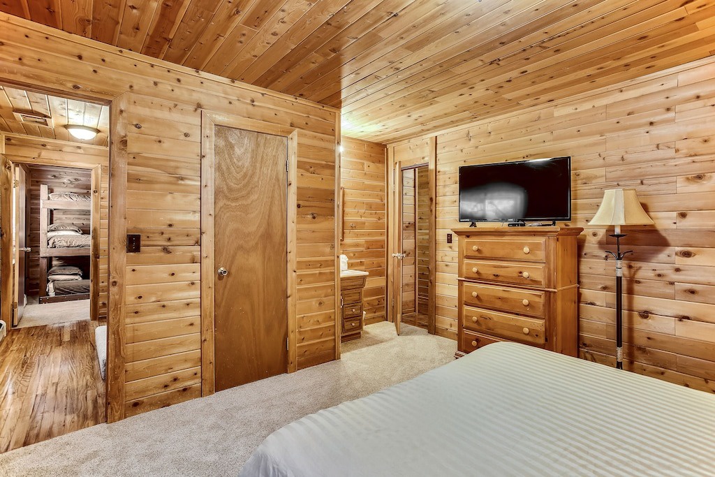 Cozy up in your rustic log cabin bedroom with warm wood walls, TV entertainment, and adjacent bunk room for the kids.