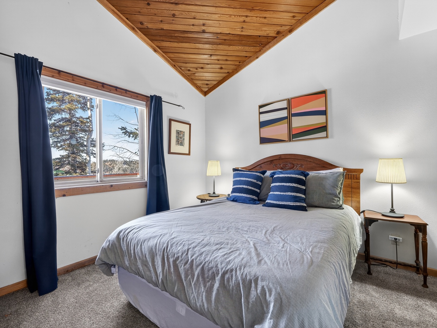 Drift off to sleep in your peaceful bedroom featuring exposed wood ceiling beams, natural light, and comfortable furnishings for a restful mountain retreat.
