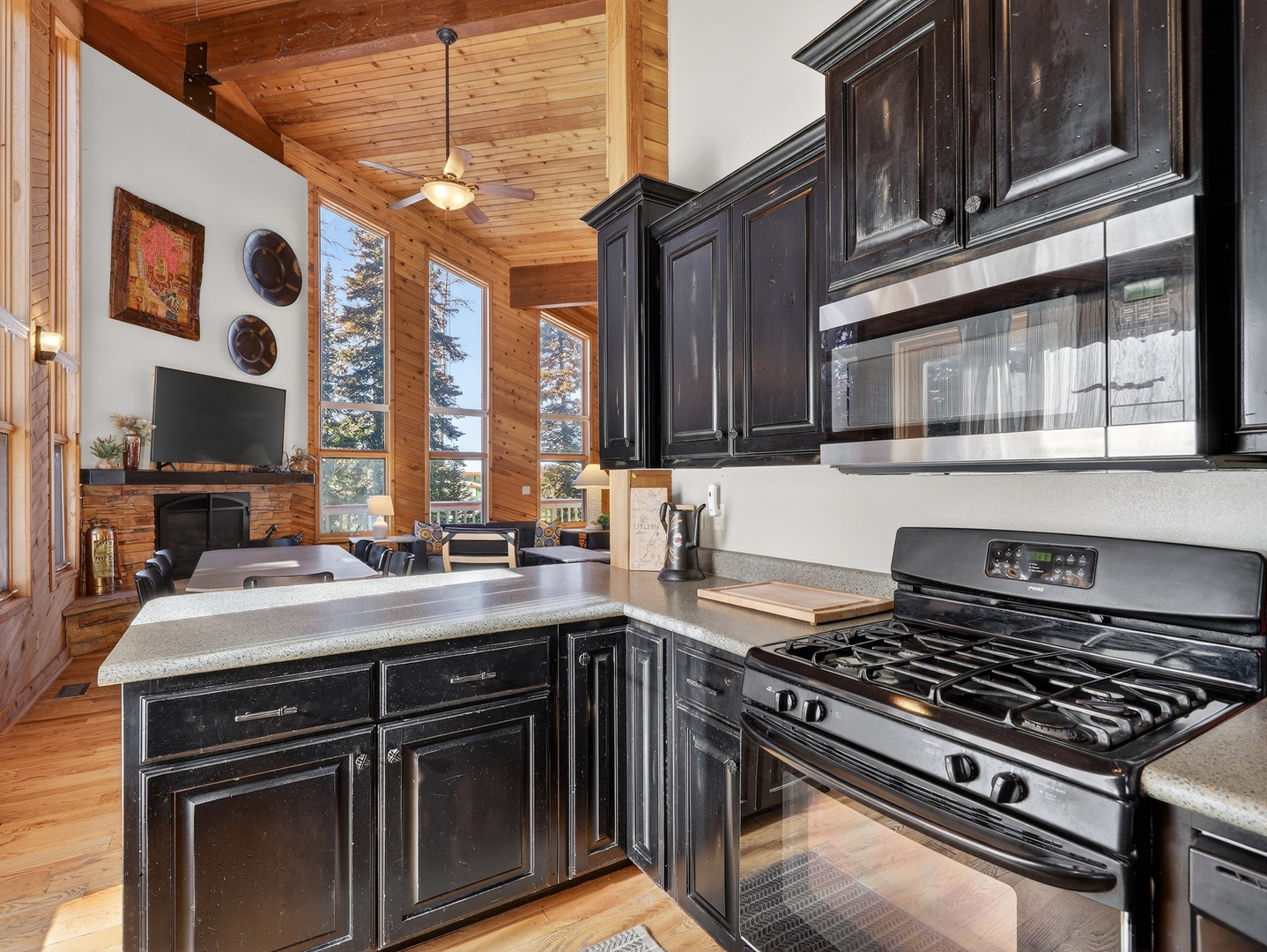 Cook your favorite meals in this beautifully appointed kitchen with dark cabinetry and modern appliances, all while enjoying forest views.