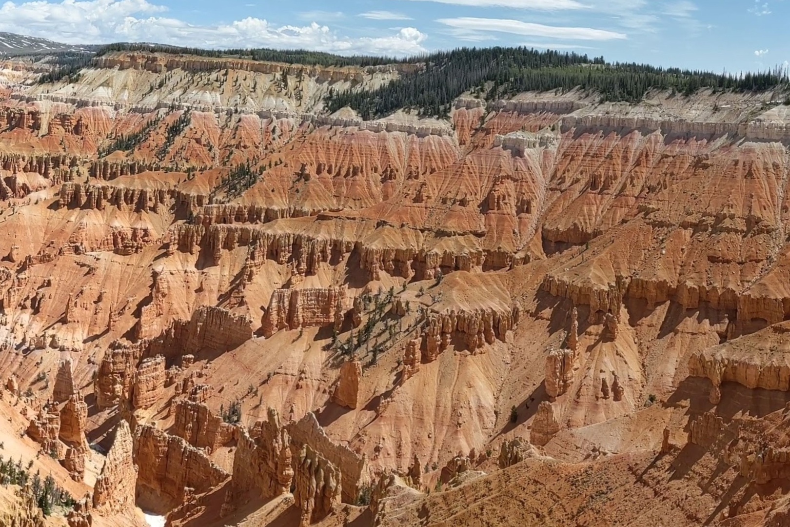 A stunning panoramic view of dramatic red-rock hoodoos and canyon formations surrounded by forested ridges under expansive skies—a remarkable natural landmark near the property.
