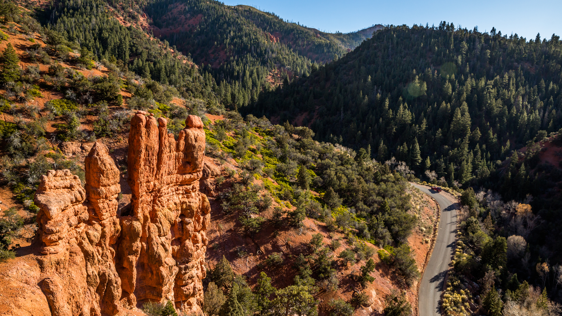 Dramatic red rock formations stand sentinel over forested mountains and a winding road—a striking natural landmark anchoring this vacation property's remarkable surroundings.