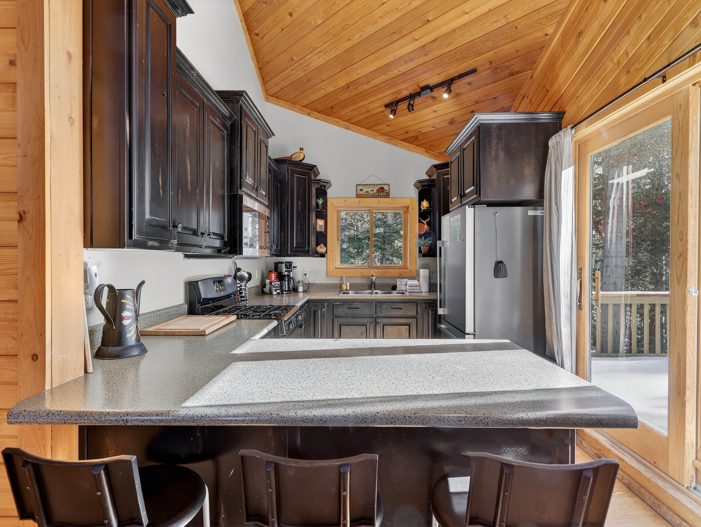 Your fully-equipped kitchen features rich wood cabinetry and spacious granite countertops, perfect for preparing memorable meals during your mountain getaway.