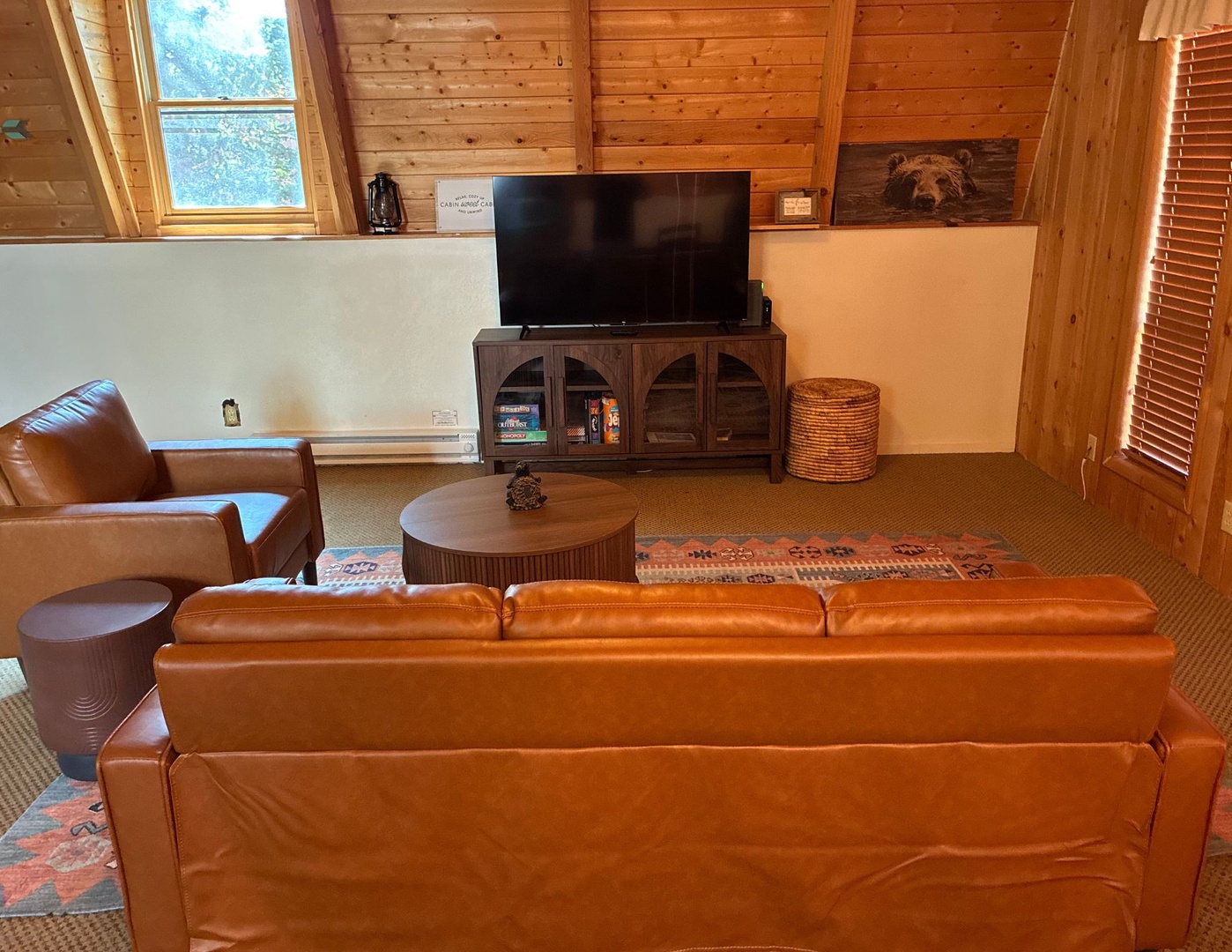 View of the living room, featuring a 55" Smart TV, comfortable couch, and views of the trees