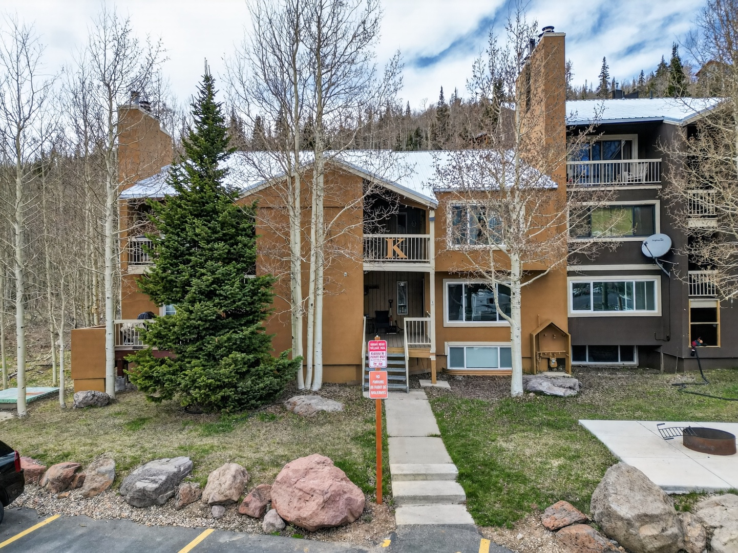 Multi-level mountain townhomes nestled among aspen and evergreen trees, with convenient parking and balconies overlooking the forested hillside.
