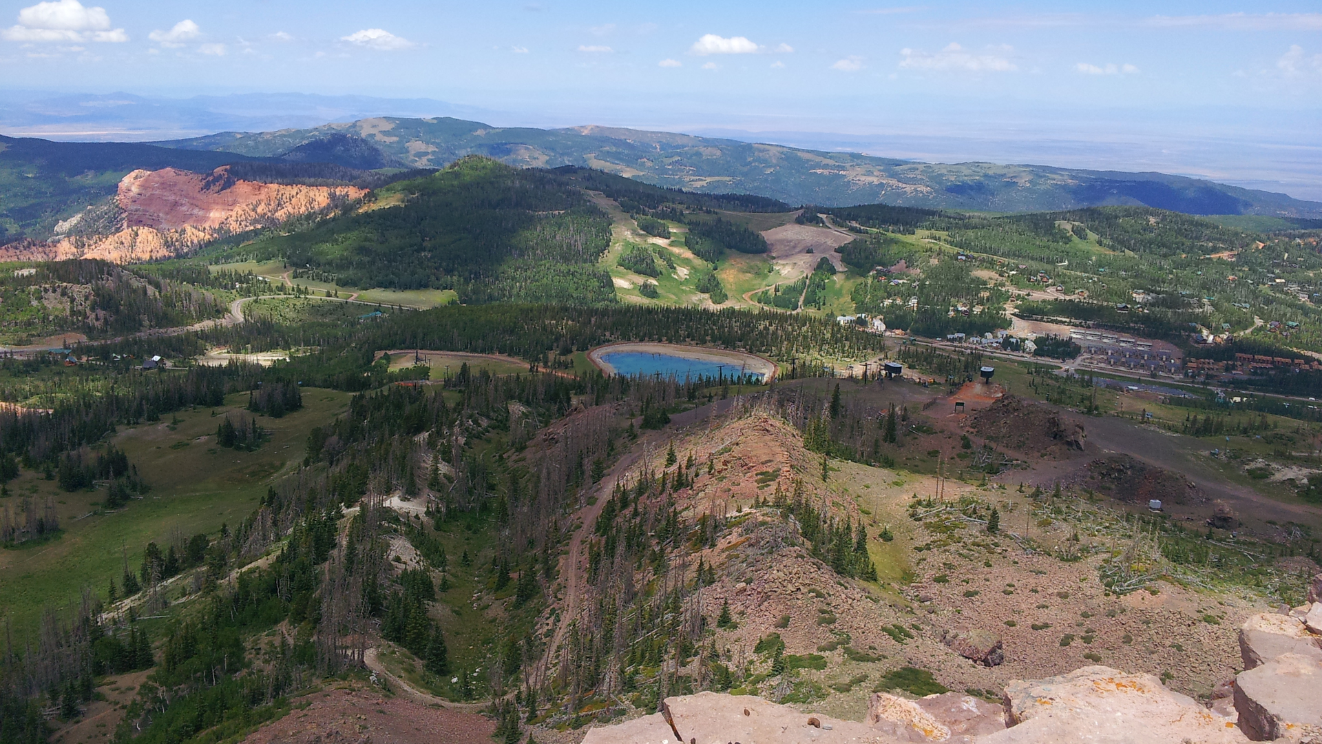 Sweeping aerial view of rolling mountains, forests, and a distant lake in the surrounding area, showcasing the scenic natural landscape near the property.