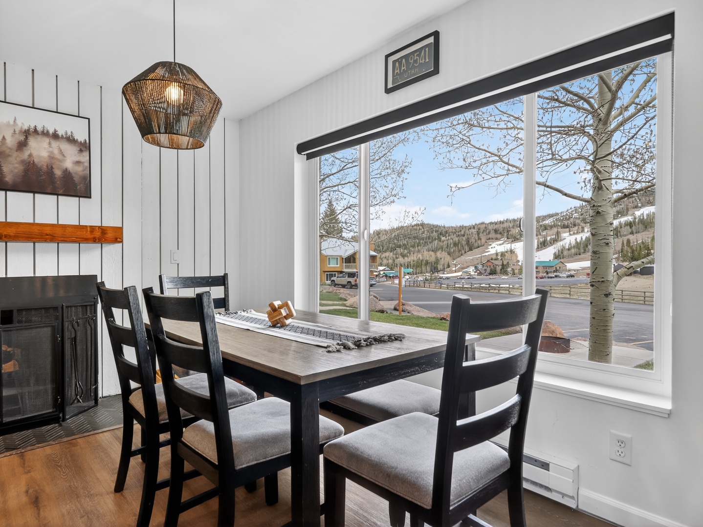Gather around this inviting dining table where stunning mountain views frame every meal. The warm fireplace and stylish lighting create a cozy ambiance for memorable moments together.