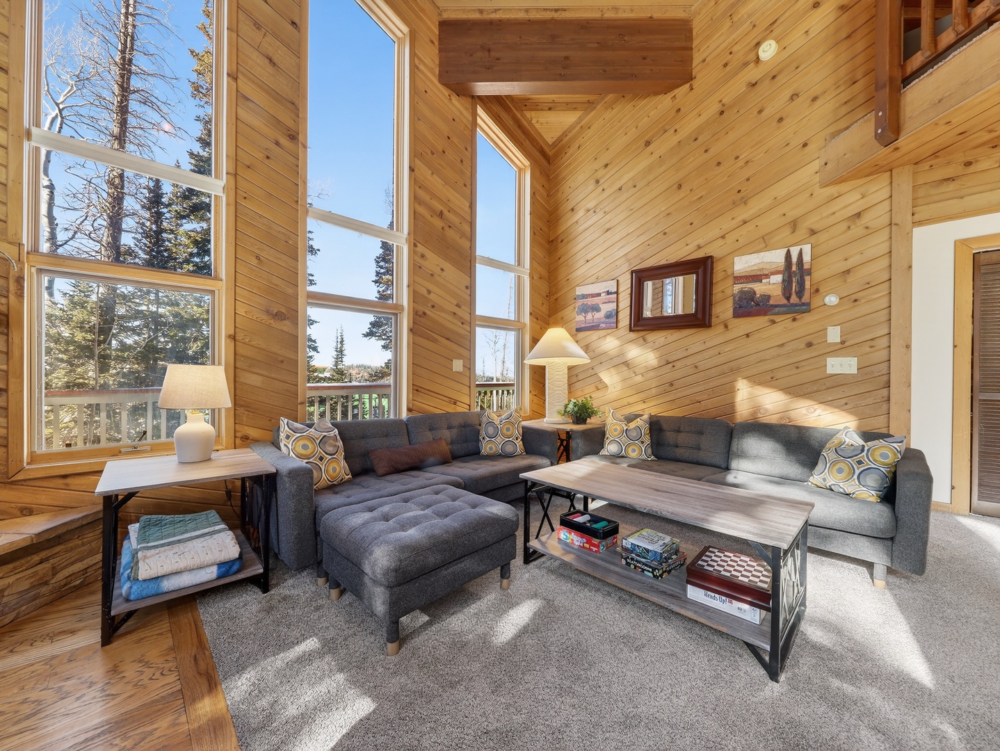 Sink into the plush sectional sofa surrounded by warm wood walls and floor-to-ceiling windows that frame stunning forest views.