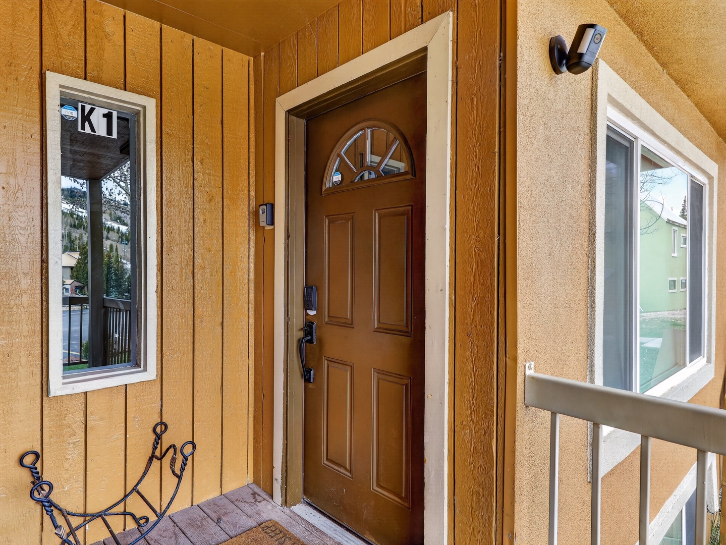 Welcoming entrance marked K1 with wood door and mountain view window.