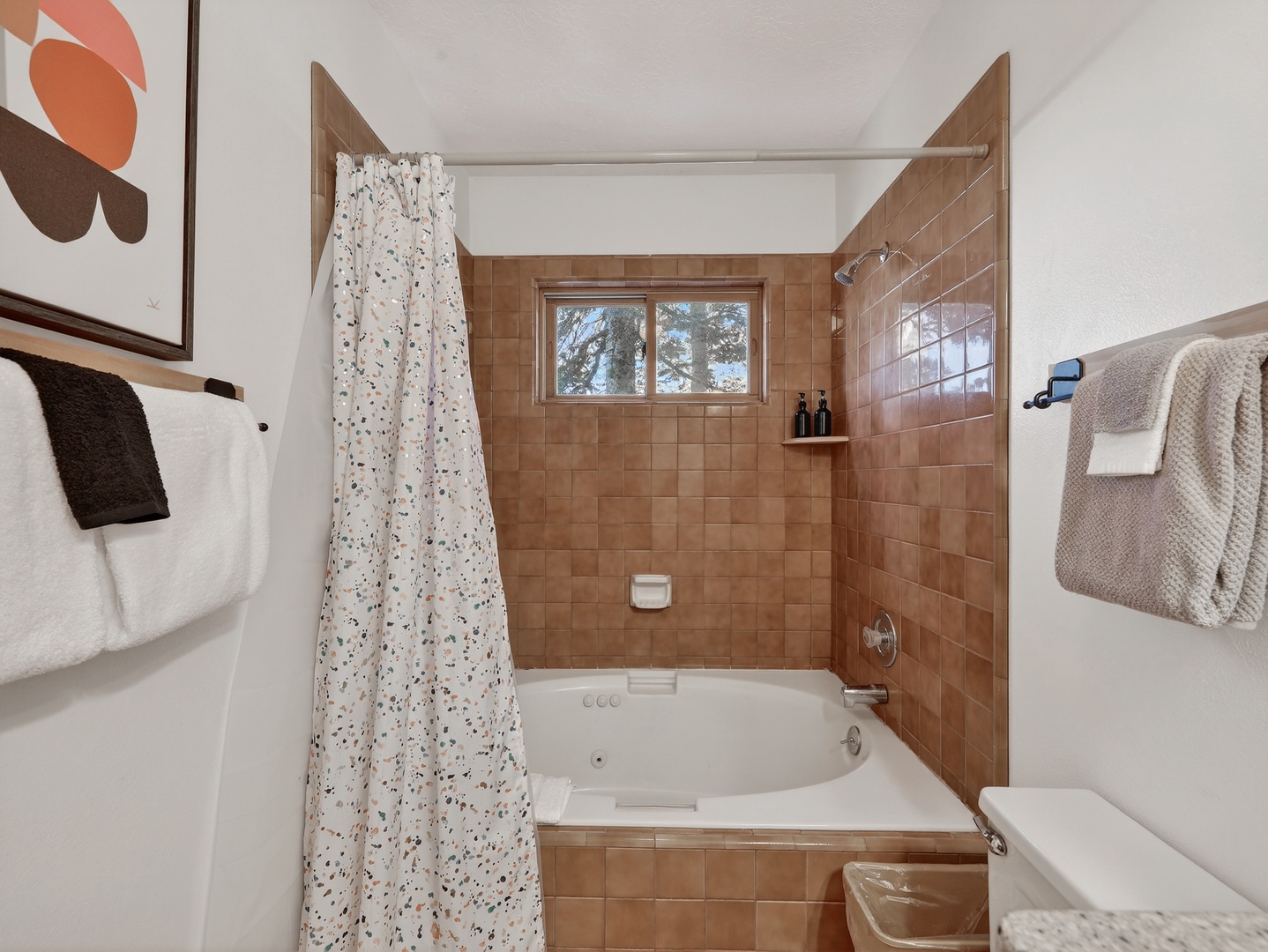 Soak in your private tub surrounded by warm brown tile and natural light from the window above.