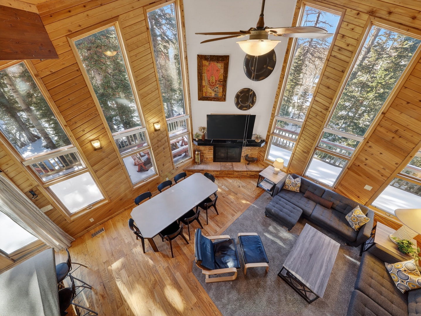 Soaring ceilings and floor-to-ceiling windows surround you with forest views while you relax by the fireplace in this stunning open-concept living space.