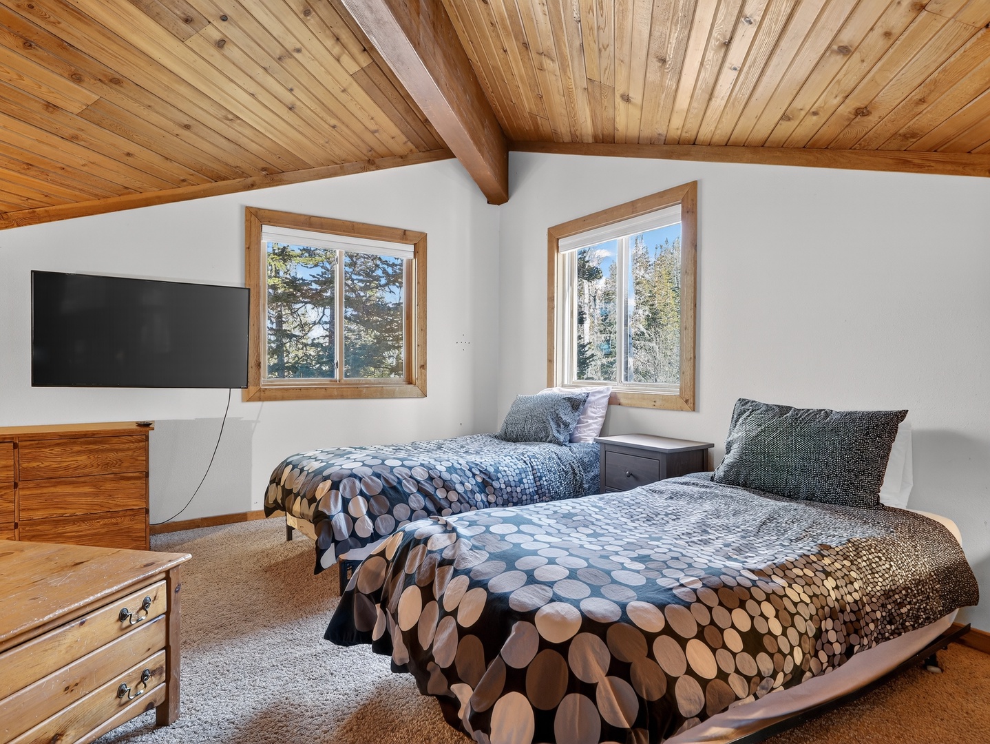 Unwind in your cozy bedroom with twin beds beneath stunning vaulted wood ceilings and mountain views.