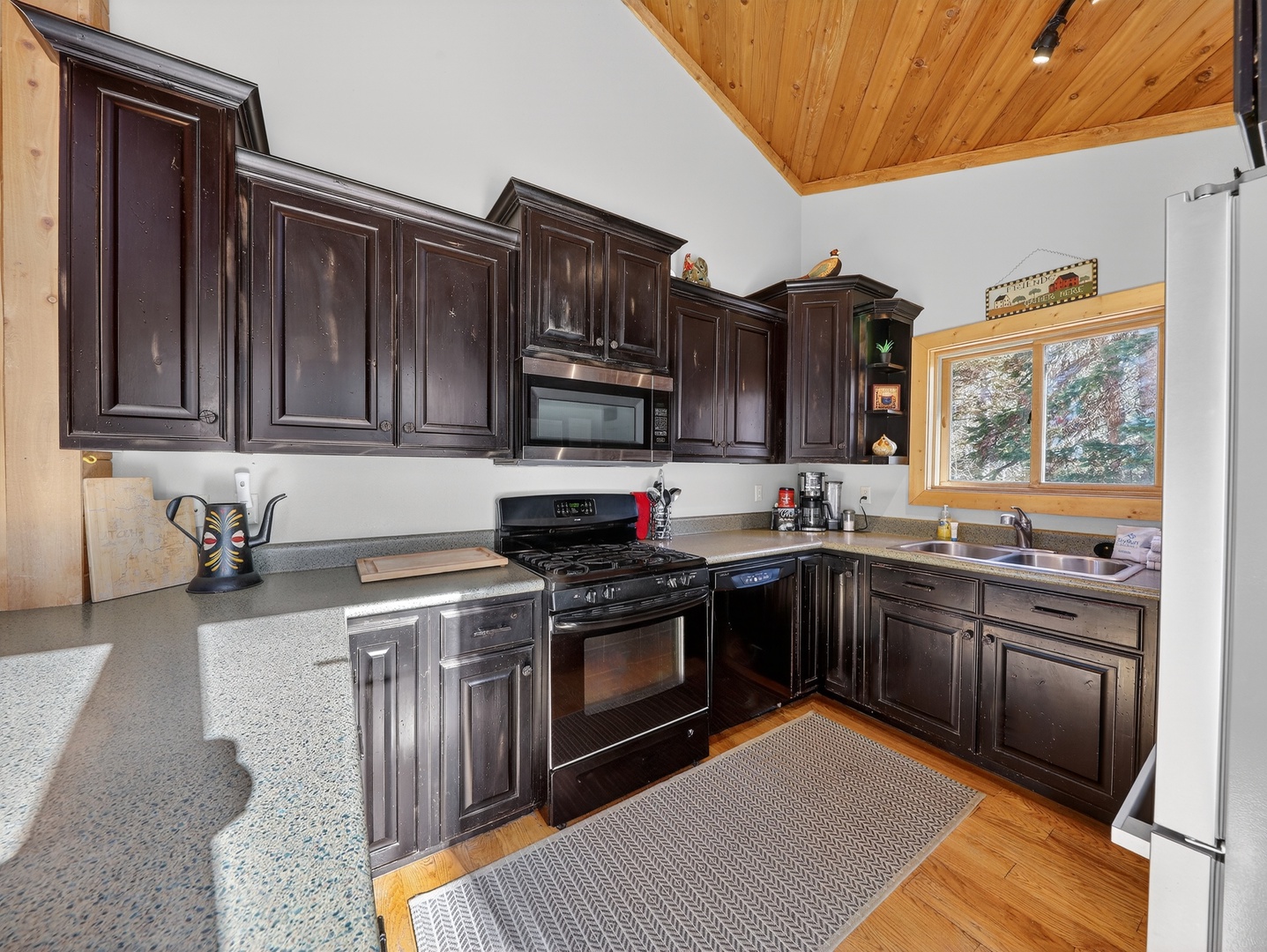 Your fully equipped kitchen awaits with dark cabinetry, modern appliances, and warm wood accents for memorable meals.