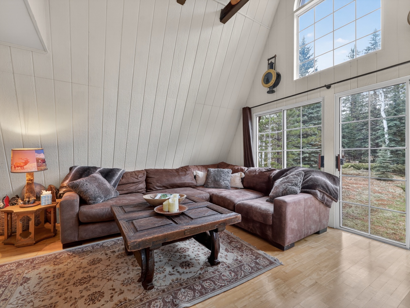 Light-filled A-frame living space with cozy seating and views of the surrounding pines