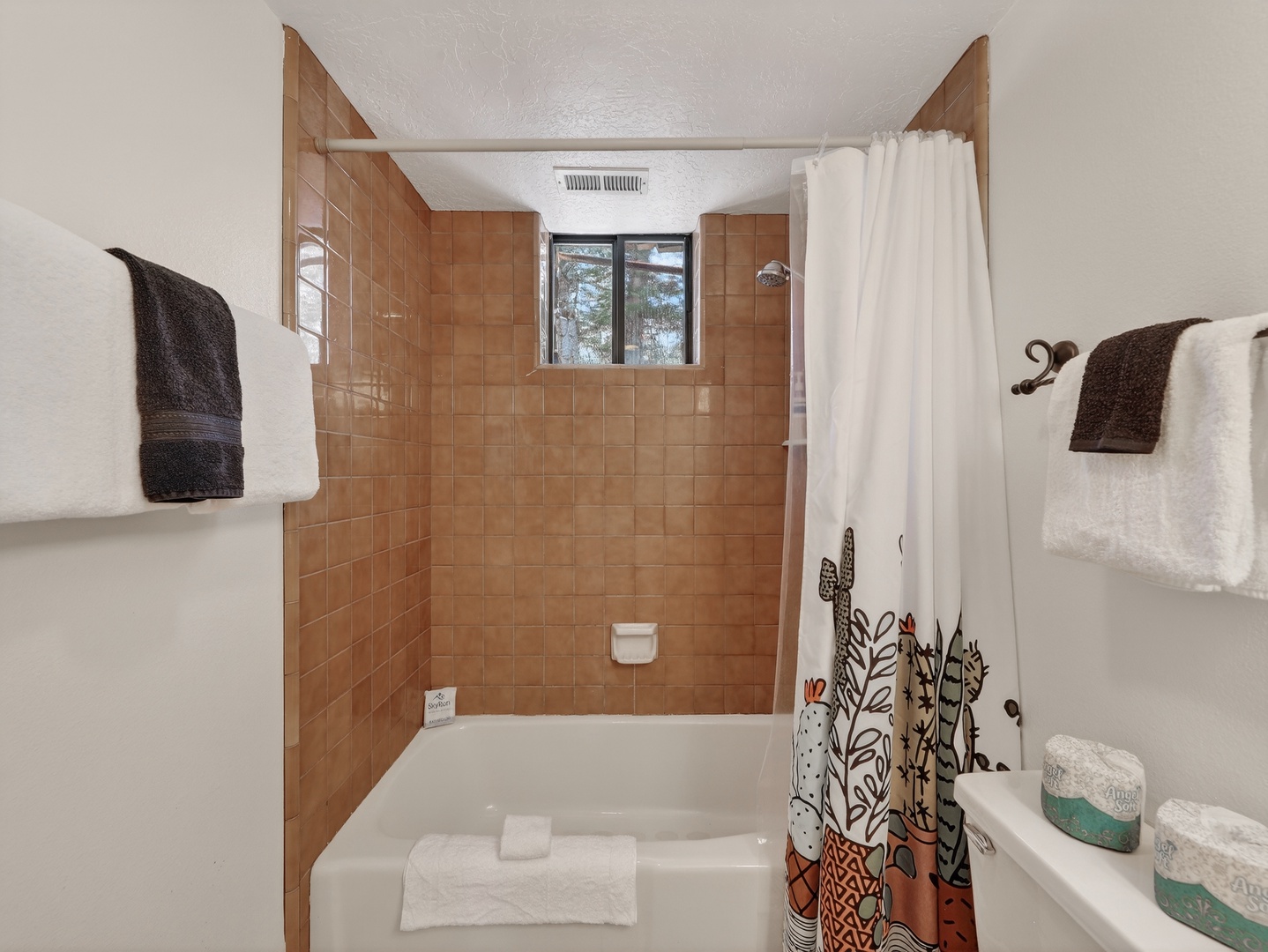 Unwind in your private bathroom featuring a full tub-shower combo with charming botanical curtain and fresh towels.