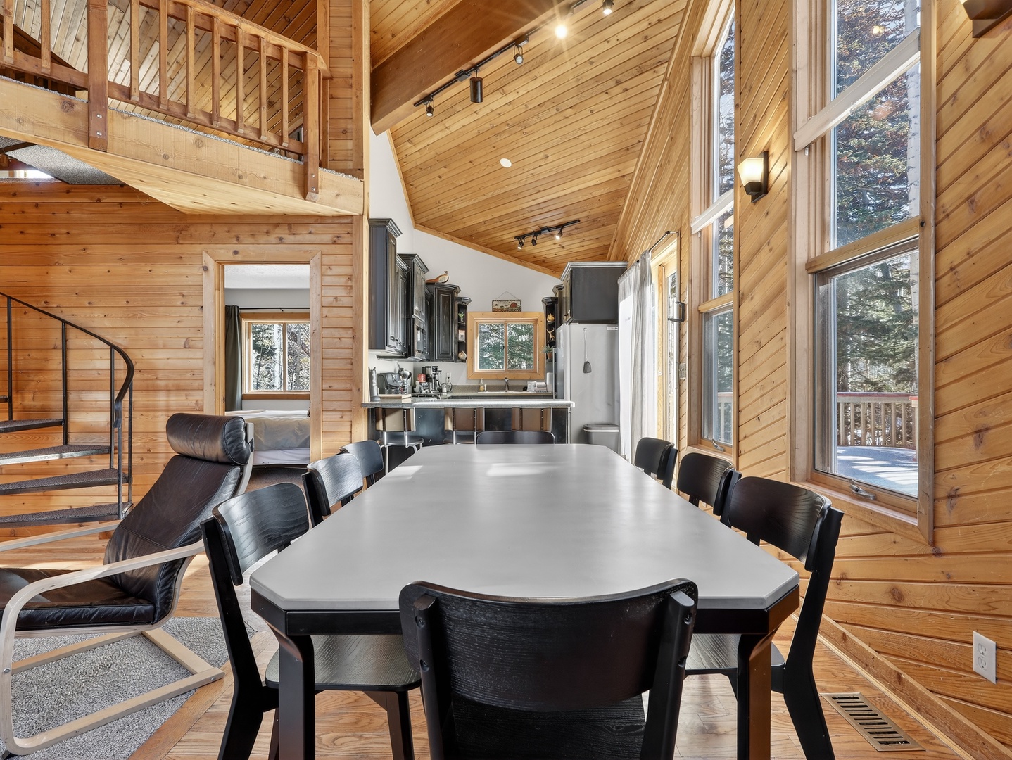 Your dining space features soaring wood ceilings and floor-to-ceiling windows that flood the room with natural light and forest views.