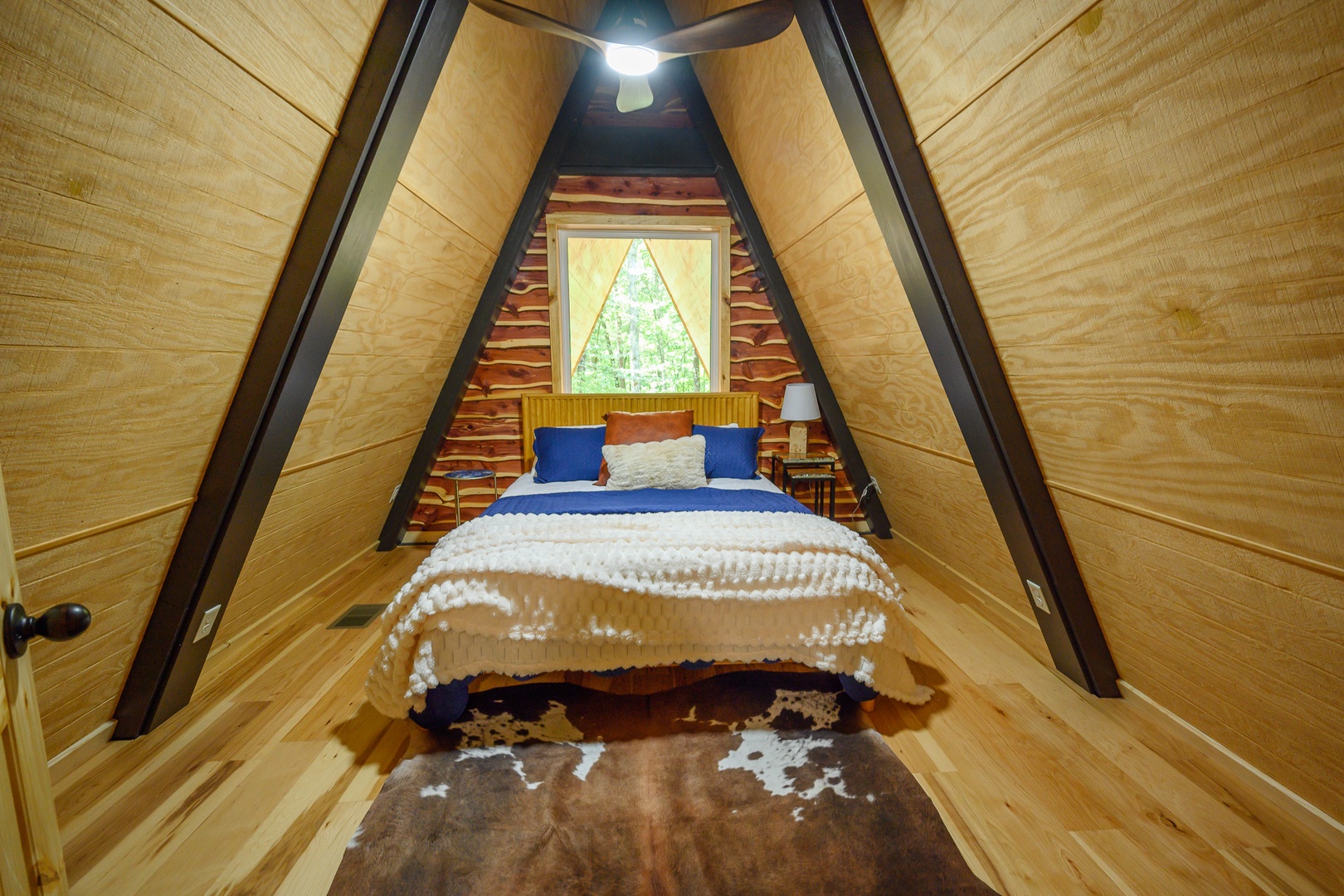 Step into your cozy A-frame retreat, where warm wood surrounds you and a cloud-soft bed beckons beneath soaring cathedral ceilings. Wake to green forest views framed perfectly by the triangular window above your headboard.