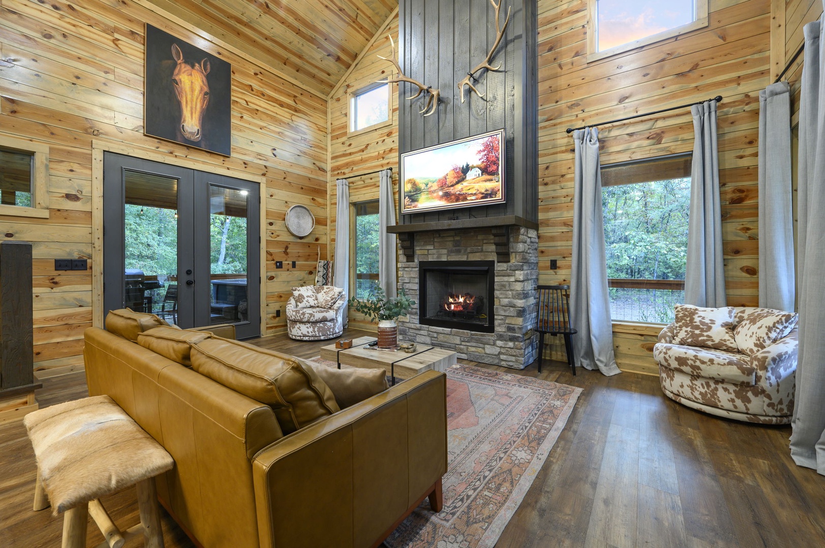 Relax in your spacious, light-filled living room with vaulted ceilings, cozy fireplace, and plush seating. Floor-to-ceiling windows frame peaceful wooded views, making this the perfect space to unwind.